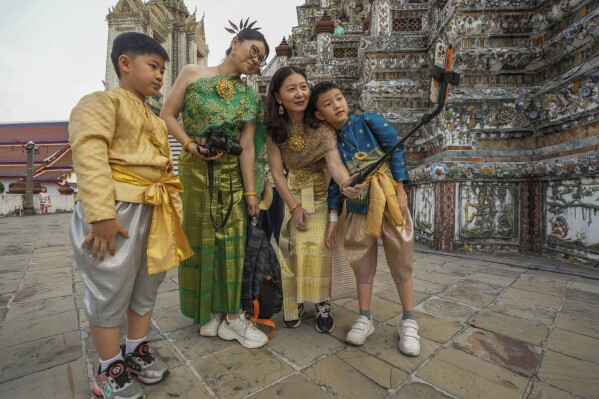 FILE - Chinese family tourists rent traditional Thai costumes and take selfies at Wat Arun, or the "Temple of Dawn," in Bangkok, Thailand, on Jan. 12, 2023. Thailand's new cabinet has approved a temporary visa exemption for tourists from China and Kazakhstan in its first meeting on Wednesday, Sept. 13, for a bid to boost tourism and the economy. (AP Photo/Sakchai Lalit, File)
