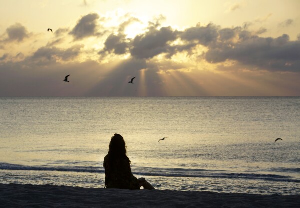 FILE - A woman meditates on the beach in Miami Beach, Fla., on April 28, 2010. Research shows a daily meditation practice can reduce anxiety, improve overall health and increase social connections, among other benefits. (AP Photo/Lynne Sladky, File)