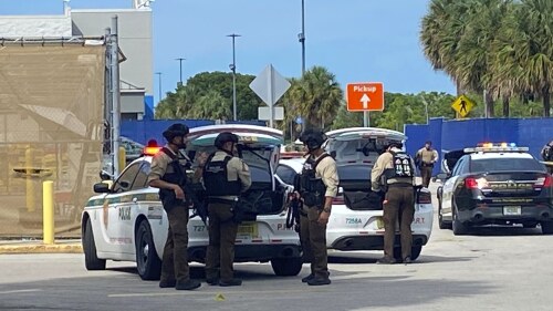 Police surround a Walmart in Florida City, Fla., about 25 miles (40 kilometers) southwest of Miami, Wednesday, July 19, 2023, after a shooting that left one person dead and another wounded. Three men are facing charges Thursday, July 20, after the shooting. (David Goodhue/Miami Herald via AP)