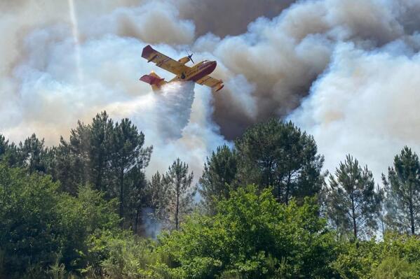 This photo provided by the fire brigade of the Gironde region (SDIS 33) shows a Canadair plane fighting wildfire near La Teste-de-Buch, southwestern France, Saturday, July 16, 2022. Strong winds and hot, dry weather are frustrating French firefighters' efforts to contain a huge wildfire that raced across pine forests in the Bordeaux region Saturday for a fifth straight day, one of several scorching Europe in recent days. (SDIS 33 via AP)
