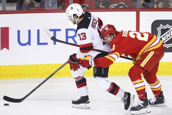 New Jersey Devils' Nico Hischier, left, reaches for the puck as Calgary Flames' Kevin Rooney defends during the first period of an NHL hockey game Saturday, Nov. 5, 2022, in Calgary, Alberta. (Larry MacDougal/The Canadian Press via AP)
