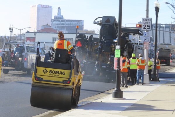 Heavy equipment repaves part of Atlantic Avenue in Atlantic City, N.J. on Dec. 13, 2023 as the city's controversial "road diet" project to narrow the main roadway from two lanes in each direction to one began. Five casinos and a hospital are asking a judge to order a halt to the plan, saying it could dangerously worsen traffic in the seaside gambling resort. (AP Photo/Wayne Parry)