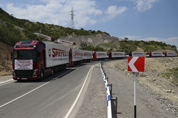 Trucks with humanitarian aid for Artsakh parked in a road towards the separatist region of Nagorno-Karabakh, in Armenia, Friday, July 28, 2023. The former chief prosecutor of the International Criminal Court warned that Azerbaijan is preparing genocide against ethnic Armenians in its Nagorno-Karabakh region and called for the UN Security Council to bring the matter before the ICC. A report by Luis Moreno Ocampo issued Tuesday said Azerbaijan's blockade of the only road leading from Armenia to Nagorno-Karabakh seriously impedes food, medical supplies and other essentials to the region of about 120,000 people. (Hayk Manukyan/PHOTOLURE via AP)