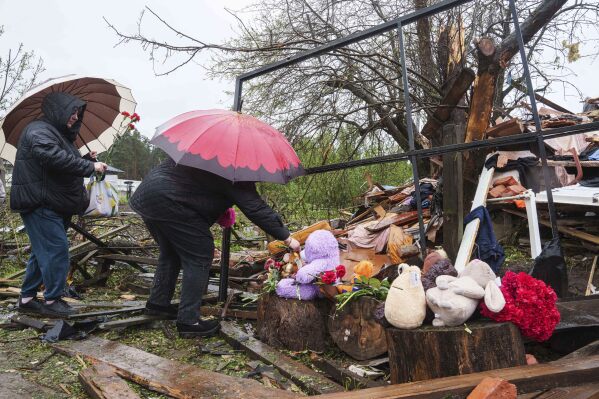 Women put flowers to the rubble of a destroyed house where three children were killed by a Russian strike in Korostyshiv, Zhytomyr region, Ukraine, Sunday, May 25, 2025. (AP Photo/Evgeniy Maloletka)