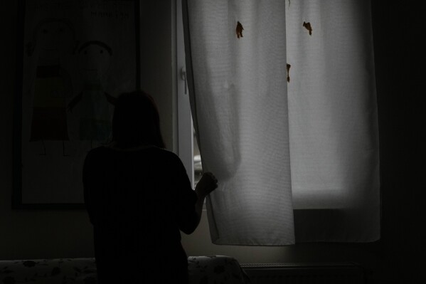A 26-year-old woman, who will not give her name for security reasons, looks out the window at a safe house for women in Belgrade, Serbia, Thursday, Nov. 23, 2023.  She said her partner repeatedly raped, beat and assaulted her.  Strangled her and kept her and the child locked in his flat for hours.  Throughout the Western Balkans, women are often harassed, raped, beaten, and killed by their partners and after repeatedly reporting the violence to authorities.  (AP Photo/Darko Vojinovic)