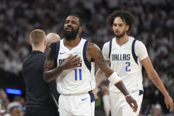 Dallas Mavericks guard Kyrie Irving (11) winks after a score against the Minnesota Timberwolves as he walks in front of Mavericks center Dereck Lively II (2) during the first half of Game 5 of the Western Conference finals in the NBA basketball playoffs, Thursday, May 30, 2024, in Minneapolis. (AP Photo/Abbie Parr)
