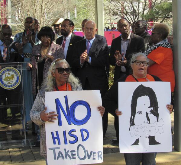 FILE - People hold up signs at a news conference, Friday, March 3, 2023, in Houston while protesting the proposed takeover of the city's school district by the Texas Education Agency. Texas officials on Wednesday, March 15, announced a state takeover of Houston's nearly 200,000-student public school district, the eighth-largest in the country, acting on years of threats and angering Democrats who assailed the move as political. (AP Photo/Juan A. Lozano)