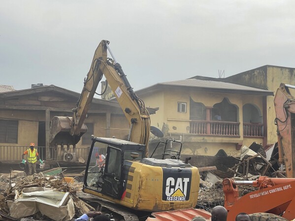 A digger removes debris from the site of a collapsed building in Abuja, Nigeria. Thursday, Aug. 24, 2023. A two-storey building collapsed in Nigeria's capital on Wednesday night, killing two people with many feared trapped amid frantic rescue efforts, emergency officials and residents told The Associated Press. (AP Photo/Chinedu Asadu)