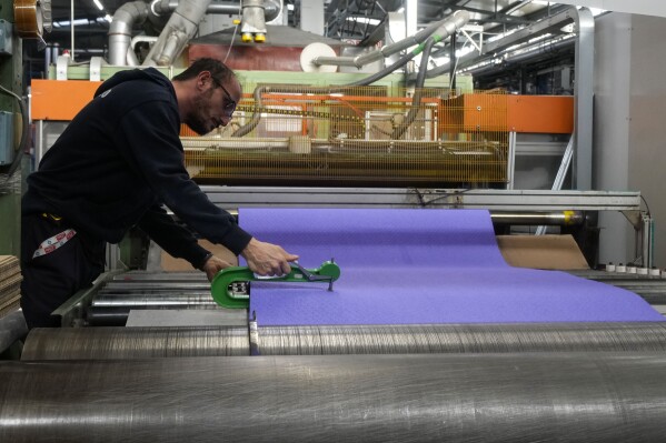 A worker checks the final surface of an athletics track, at the Mondo factory, in Alba, northern Italy, Wednesday, March 13, 2024. The athletics track for the upcoming Paris Olympics is being produced by the Mondo company at its factory in northern Italy. The track is made in portions, rolled up and then will be transported to the Stade de France, where it will be installed over the next month. (AP Photo/Luca Bruno)