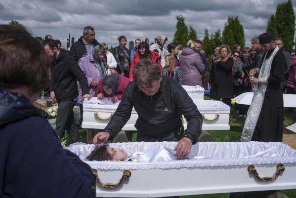A father mourns his children Roman Martyniuk, 17, Tamara Martyniuk, 8, and Stanislav Martyniuk, 12, killed in a Russian strike on Sunday, during farewell ceremony in Korostyshiv, Zhytomyr region, Ukraine, Wednesday, May 28, 2025. (AP Photo/Evgeniy Maloletka)