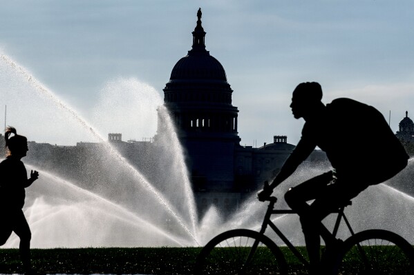 FILE - The Capitol is seen as water sprinklers soak the National Mall on a hot summer morning in Washington, July 15, 2022. A new poll finds that most Americans share many core values on what it means to be an American despite the country’s deep political polarization. The poll from The Associated Press-NORC Center for Public Affairs Research found that about 9 in 10 U.S. adults say the right to vote, the right to equal protection under the law and the right to privacy are important or very important to the U.S.’s identity as a nation.(AP Photo/J. Scott Applewhite)