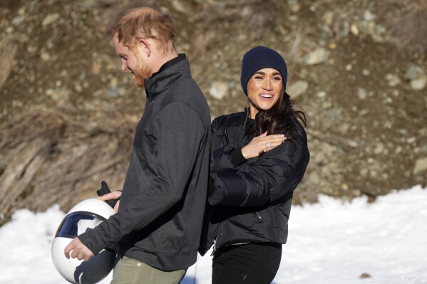 Britain's Prince Harry and Meghan, the Duke and Duchess of Sussex, walk together after Harry slid down the track on a skeleton sled a second time while attending an Invictus Games training camp, in Whistler, British Columbia, Thursday, Feb. 15, 2024. (Darryl Dyck/The Canadian Press via AP)