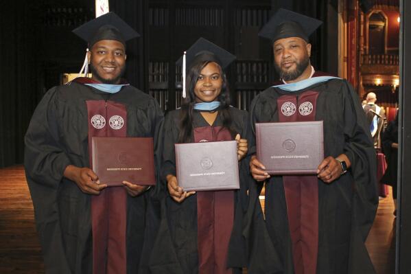 In this photo provided by Mississippi State University - Meridian Office of Public Affairs, Ja'Coby Cole, left, his sister Iesha Gully and their father Commondre Cole, right, show their diploma covers, on Thursday, May 12, 2022, during the school's commencement at the MSU Riley Center in Meridian, Miss. Each of the three earned a master's degree in education. (Lisa Sollie/Mississippi State University - Meridian via AP)