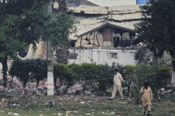 Local residents walk through rubble of a building damaged by a suspected Indian missile attack, in Muridke, a town in Pakistan's Punjab province, Wednesday, May 7, 2025. (AP Photo/K.M. Chaudary)