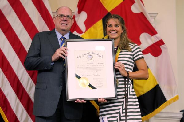 Maryland Gov. Larry Hogan, left, presents a citation to Becca Meyers on Monday, July 26, 2021 in Annapolis, Md., recognizing her "bravery for highlighting the issue of inequality and access for people with disabilities." Meyers, a Maryland native who is deaf and blind and won three gold medals in the last Paralympics, withdrew from the Tokyo games because she could not bring her mother with her as her personal care assistant. (AP Photo/Brian Witte)
