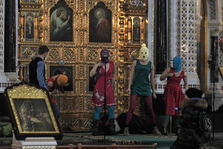 FILE - Members of the Russian feminist group Pussy Riot protest inside the Christ the Savior Cathedral in Moscow, Tuesday, Feb. 21, 2012 . Over the last decade, Vladimir Putin's Russia evolved from a country that tolerates at least some dissent to one that ruthlessly suppresses it. Arrests, trials and long prison terms — once rare — are commonplace. (AP Photo, File)