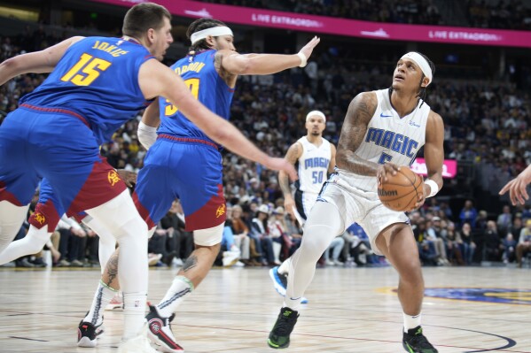 Orlando Magic forward Paolo Banchero, right, looks to shoot as Denver Nuggets center Nikola Jokic, left, and forward Aaron Gordon, center, defend in the first half of an NBA basketball game Friday, Jan. 5, 2024, in Denver. (AP Photo/David Zalubowski)