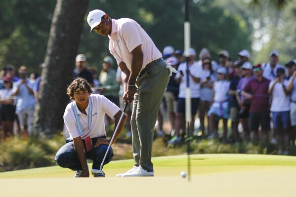 Tiger Woods putts as his son Charlie, watches on the seventh hole during a practice round for the U.S. Open golf tournament Tuesday, June 11, 2024, in Pinehurst, N.C. (AP Photo/George Walker IV)