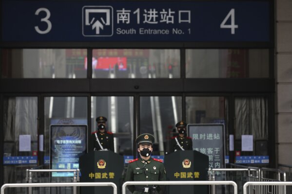 FILE - In this Jan. 23, 2020, file photo,  paramilitary police stand guard outside the closed Hankou Railway Station in Wuhan in central China's Hubei Province. A 10-member team of international researchers from the World Health Organization hopes to find clues as to the origin of the coronavirus pandemic in the central Chinese city of Wuhan where the virus was first detected in late 2019. (Chinatopix via AP, File)