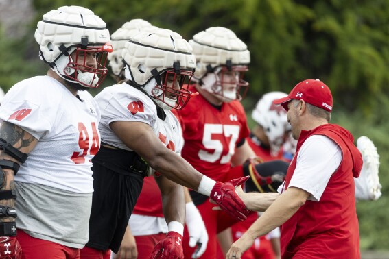 Wisconsin NCAA college football defensive coordinator Mike Tressel low-fives Wisconsin defensive end Rodas Johnson on the first day of training camp in Platteville, Wisc., Wednesday, Aug. 2, 2023. (Samantha Madar/Wisconsin State Journal via AP)