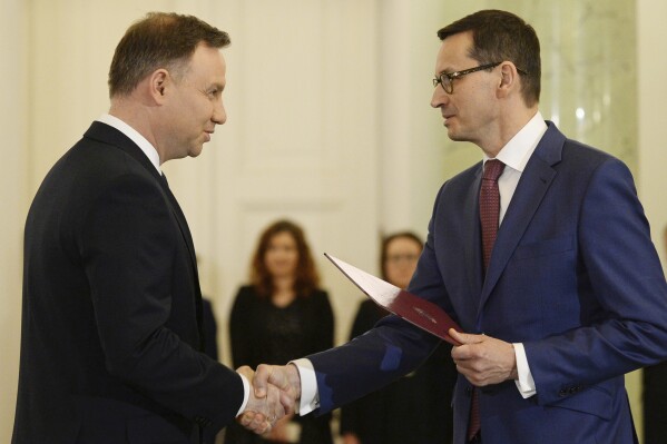 FILE - Polish President Andrzej Duda, left, designates then Finance Minister Mateusz Morawiecki, right, for the prime minister's post, in Warsaw, Poland, Friday, Dec. 8, 2017. Poland’s president Duda has tapped the outgoing prime minister, Mateusz Morawiecki of the Law and Justice party, to try to form the country’s next government. His decision is expected to delay the establishment of a functioning government because a majority of lawmakers aren't likely to give Morawiecki approval for his proposed Cabinet. (AP Photo/Alik Keplicz), File)