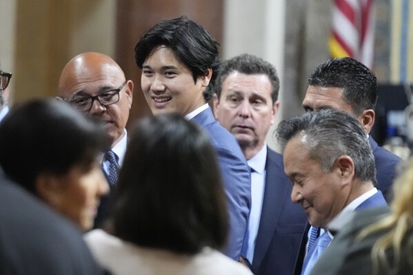 Los Angeles Dodgers baseball star Shohei Ohtani interacts with officials after being honored, Friday, May 17, 2024, during a council meeting in Los Angeles. (AP Photo/Damian Dovarganes)