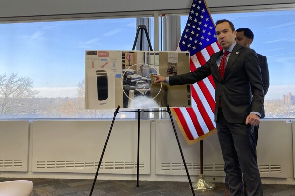 New Jersey Attorney General Matt Platkin points to a photo he says shows guns stored near a ground-floor window at a gun shop, contrary to state law, on Tuesday, Dec. 12, 2023, in Trenton, N.J. The shop was one of three gun dealers Platkin sued on Tuesday. The suits were the first brought by his office under a 2022 law aimed at holding gun dealers accountable by allowing the attorney general to sue under New Jersey's public nuisance laws. (AP Photo/Mike Catalini)