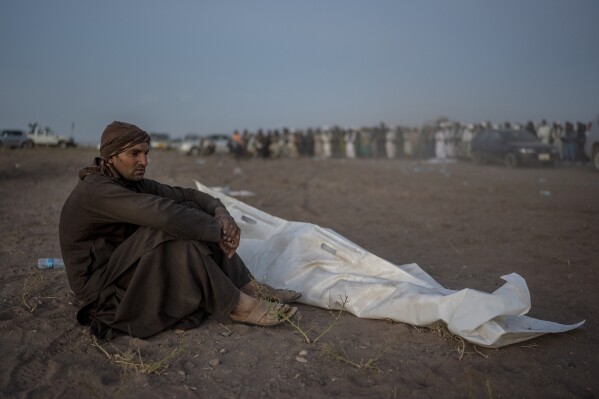 An Afghan man sits next to the body of his relative who was killed by the earthquake, at a burial site in Zenda Jan district in Herat province, western of Afghanistan, Monday, Oct. 9, 2023. Saturday's deadly earthquake killed and injured thousands when it leveled an untold number of homes in Herat province. (AP Photo/Ebrahim Noroozi)