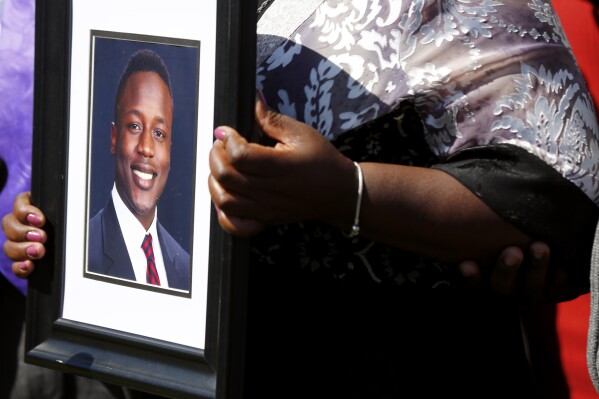 FILE - Caroline Ouko, mother of Irvo Otieno, holds a portrait of her son at the Dinwiddie Courthouse in Dinwiddie, Va., March 16, 2023. The family of Otieno, a man who died while handcuffed and pinned to the floor for about 11 minutes as he was being admitted to a Virginia psychiatric hospital, has reached an $8.5 million settlement, Wednesday, Sept. 20, 2023, with the state, county and the sheriff whose deputies were involved in restraining the man. (Daniel Sangjib Min/Richmond Times-Dispatch via AP, File)