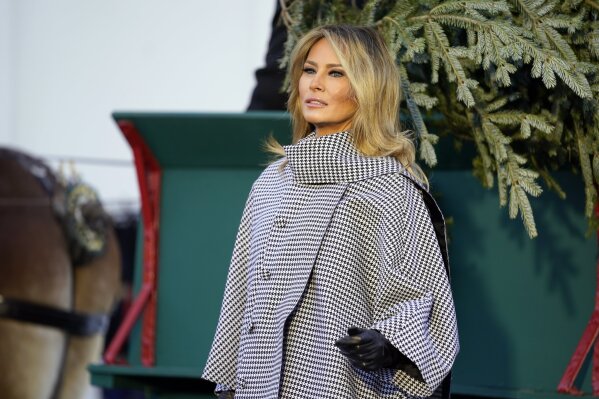 First lady Melania Trump stands next to the 2020 Official White House Christmas tree as it is presented on the North Portico of the White House, Monday, Nov. 23, 2020, in Washington. (AP Photo/Andrew Harnik)
