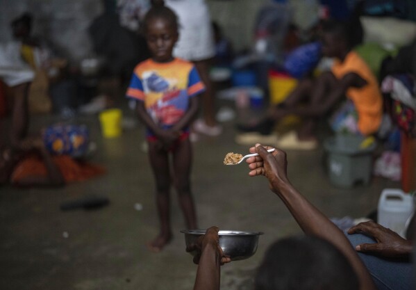 A mother tries to get her daughter to eat a spoonful of rice at a school that is housing residents displaced by gang violence in Port-au-Prince, Haiti, Wednesday, May 8, 2024. As young Haitians are increasingly exposed to violence, the country is undergoing a wider push to dispel a long-standing taboo on seeking therapy and talking about mental health. (AP Photo/Ramon Espinosa)