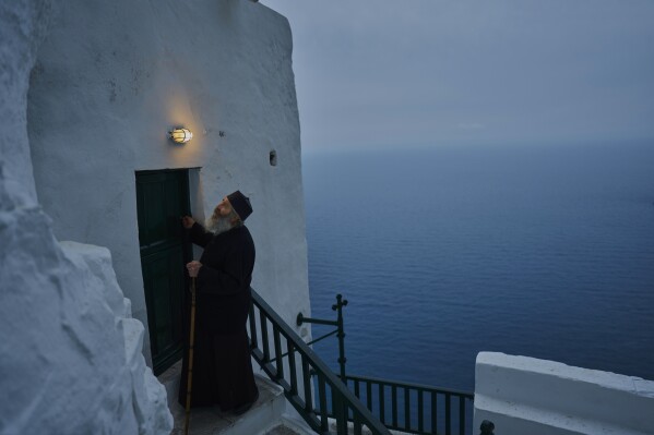 O monge cristão ortodoxo Padre Spyridon tranca a capela do Mosteiro de Panagia Hozoviotissa enquanto o Mar Egeu é visto ao fundo, na ilha de Amorgos, Grécia, na quarta-feira, 27 de março de 2025. (Foto AP/Petros Giannakouris)
