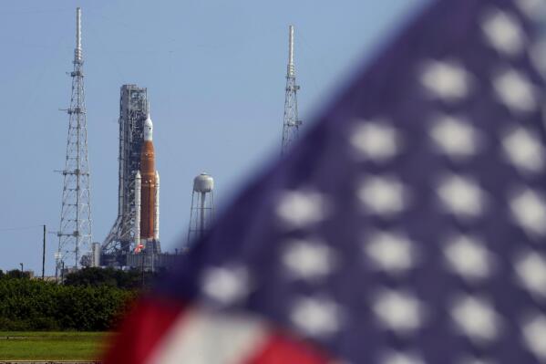 FILE - An American flag flies in the breeze as NASA's new moon rocket sits on Launch Pad 39-B after being scrubbed at the Kennedy Space Center Sept. 3, 2022, in Cape Canaveral, Fla.  It’s not just rocket fuel propelling America’s first moonshot after a half-century lull. Rivalry with China’s space program is helping drive NASA’s effort to get back into space in a big way. That's as both nations push to put people back on the moon and establish the first lunar bases. (AP Photo/Chris O'Meara, File)