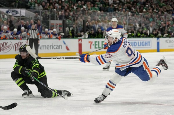 Edmonton Oilers' Connor McDavid (97) takes a shot as Dallas Stars' Sam Steel defends in the second period of an NHL hockey game, Wednesday, April 3, 2024, in Dallas. (AP Photo/Tony Gutierrez)