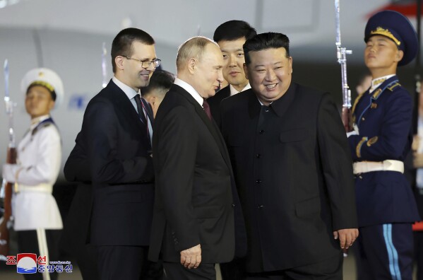 In this photo provided on Wednesday, June 19, 2024, by the North Korean government, Russian President Vladimir Putin, center, talks with North Korea's leader Kim Jong Un, center right, on Putin's arrival at the Pyongyang International Airport in Pyongyang, North Korea, early Wednesday, June 19. The content of this image is as provided and cannot be independently verified. Korean language watermark on image as provided by source reads: "KCNA" which is the abbreviation for Korean Central News Agency.(Korean Central News Agency/Korea News Service via AP)