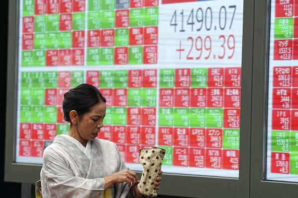 A person in traditional Japanese "kimono" walks in front of an electronic stock board showing Japan's Nikkei index at a securities firm Tuesday, July 16, 2024, in Tokyo. (AP Photo/Eugene Hoshiko)