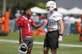 Miami Dolphins quarterback Tua Tagovailoa (1) talks to tight end Adam Shaheen (80) during an NFL football practice Saturday, July 31, 2021, in Miami Gardens, Fla. (AP Photo/Marta Lavandier)