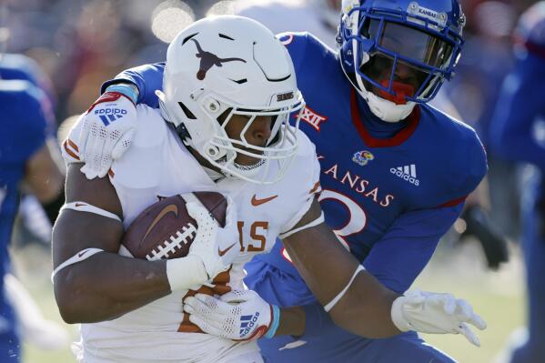 Texas running back Roschon Johnson, left, is stopped by Kansas cornerback Ra'Mello Dotson (3) during the first quarter of an NCAA college football game, Saturday, Nov. 19, 2022, in Lawrence, Kan. (AP Photo/Colin E. Braley)