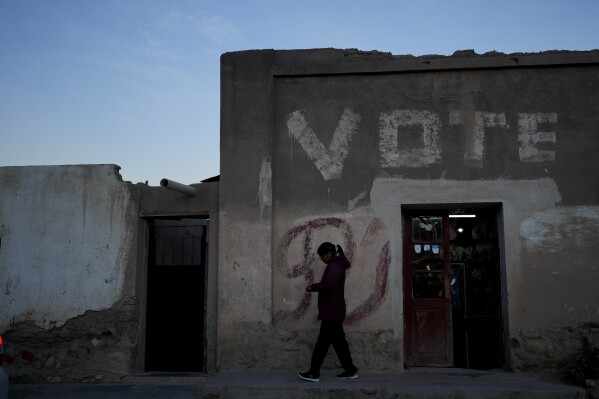 A woman walks past a building in San Antonio de los Cobres, Salta, Argentina, Tuesday, Oct. 3, 2023. In San Antonio de los Cobres presidential candidate Javier Milei got 60% of the votes in the primary elections. (AP Photo/Natacha Pisarenko)