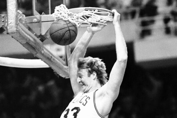 FILE - Boston Celtics Larry Bird hangs on the rim and reacts as he slams the ball through the hoop on June 12, 1984, in Boston. Celtics beat the Los Angeles Lakers 111-102 in Game 7 in the first NBA Finals between Boston's Bird and Los Angeles' Magic Johnson. (AP Photo, File)