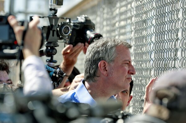 
              FILE - In this Thursday, June 21, 2018, file photo, New York City Mayor Bill de Blasio looks through a closed gate at the Port of Entry facility, in Fabens, Texas, where tent shelters are being used to house separated family members. U.S. Customs and Border Protection is alleging that de Blasio illegally crossed from Mexico into the U.S. while visiting the El Paso, Texas, area in June, an accusation the mayor’s office flatly denies. (AP Photo/Matt York, File)
            