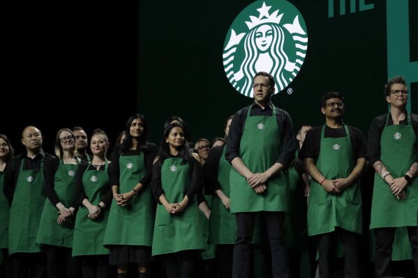 Starbucks baristas stand on stage, March 20, 2019, during an annual shareholders meeting in Seattle. (AP Photo/Ted S. Warren, file)