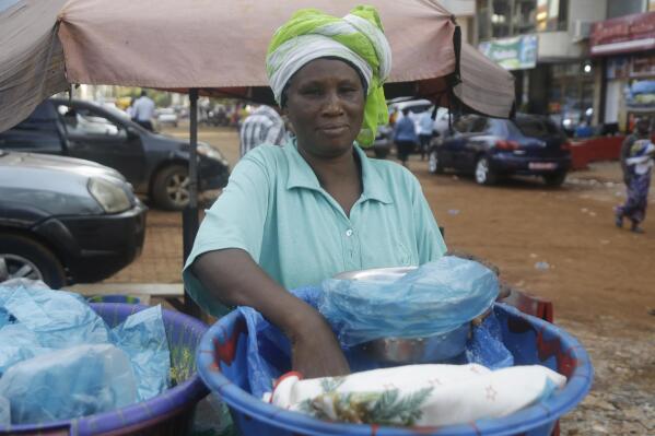 A woman sells food on a street in Conakry, Guinea, Wednesday, Sept. 8, 2021. Guinea's new military leaders sought to tighten their grip on power after overthrowing President Alpha Conde, warning local officials that refusing to appear at a meeting convened Monday would be considered an act of rebellion against the junta. (AP Photo/Sunday Alamba)