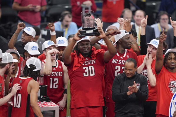 North Carolina State forward DJ Burns Jr. (30) hoists the MVP trophy as he joins his teammates as they celebrate winning an NCAA college basketball game against North Carolina to win the championship of the Atlantic Coast Conference tournament, Saturday, March 16, 2024, in Washington. North Carolina State won 84-76.(AP Photo/Susan Walsh)