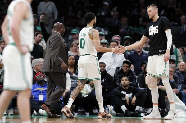 Boston Celtics' Jayson Tatum (0) leaves the court past Kristaps Porzingis, right, after being ejected for his second technical foul during the second half of the team's NBA basketball game against the Houston Rockets, Saturday, Jan. 13, 2024, in Boston. (AP Photo/Michael Dwyer)