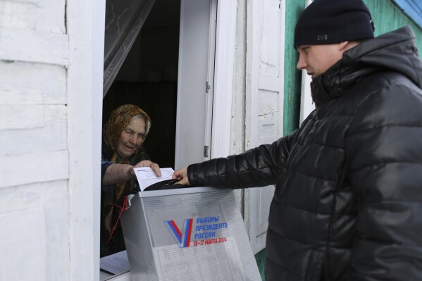 An elderly woman casts a ballot during a presidential election via a mobile election committee, who visit people who cannot physically attend a polling station, in Nikolayevka village outside Siberian city of Omsk, 2236 km (1397 miles) east of Moscow, Russia, on Saturday, March 16, 2024. Voters in Russia are heading to the polls for a presidential election that is all but certain to extend President Vladimir Putin's rule after he clamped down on dissent. (AP Photo)