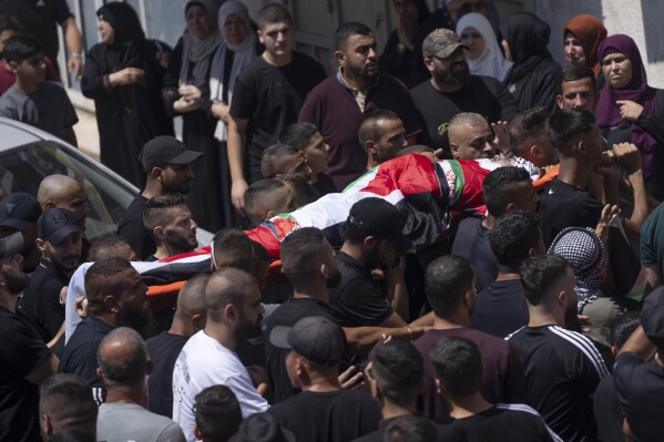 Mourners carry the body of Mahmoud Jarad, 23, during his funeral in the West Bank city of Tulkarem, Friday, Aug. 11, 2023. The Israeli military stormed into a refugee camp in the northern occupied West Bank on Friday, sparking a firefight with Palestinian gunmen and killing the 23-year-old militant, Palestinian authorities said. (AP Photo/Nasser Nasser)