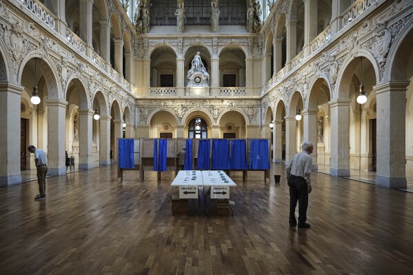 Voters wait at a polling station to vote in the first round of the French parliamentary election, in Lyon, central France, Sunday, June 30, 2024. (AP Photo/Laurent Cipriani)