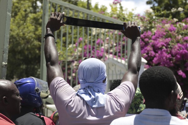 FILE - A protester holds up a machete as a symbol of self-defense against gangs, during a protest against gang violence in Port-au-Prince, Haiti, Friday, Aug. 25, 2023. Kenya’s president is committing his country to lead a multinational force in Haiti to combat gang warfare even as residents of both countries question the plan being pushed by the United States government. President William Ruto was speaking Wednesday, Sept. 20 at a ceremony establishing diplomatic ties with the Caribbean nation. (AP Photo/Odelyn Joseph, file)