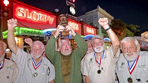 In this Saturday, July 22, 2023, photo provided by the Florida Keys News Bureau, Gerrit Marshall, center, hoists his trophy after winning the Hemingway Look-Alike Contest at Sloppy Joe's Bar in Key West, Fla.  After 11 years of competing Marshall, a Madison, Wisc., resident, finally achieved success on his 68th birthday.  Flanking Marshall, from left, are previous winners including Tom Grizzard, Wally Collins and John Stubbings.  The competition was a highlight of the annual Hemingway Days festival that ends Sunday, July 23. Ernest Hemingway lived in Key West throughout most of the 1930s.  (Andy Newman/Florida Keys News Bureau via AP)